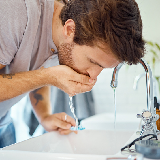 Man leaning over sink about to spit out mouthwash