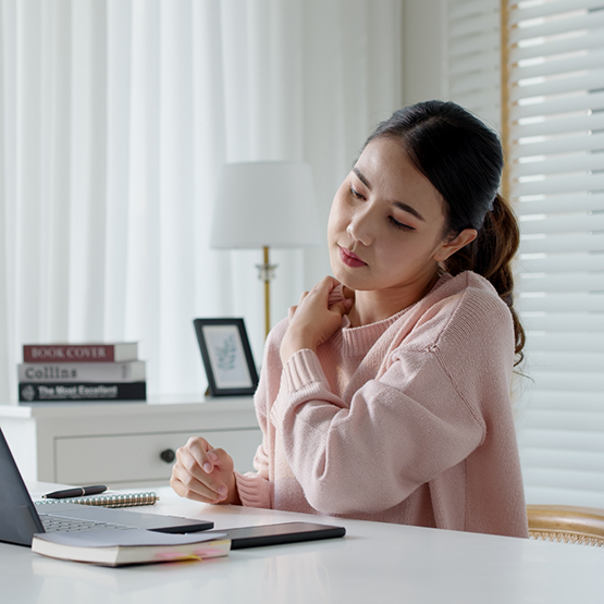 Woman at desk rubbing her shoulder