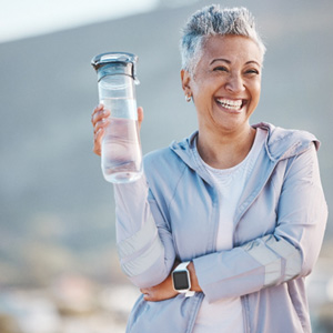 Woman smiling with water bottle on hike outside