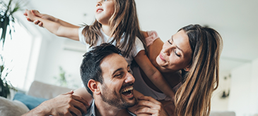 Man giving little girl piggyback ride and looking at woman