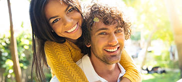 Man in white shirt giving woman in yellow shirt a piggyback ride