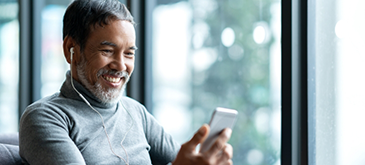 Bearded man smiling and looking at phone